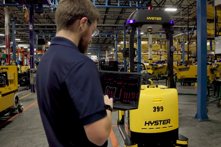 Man operates a Hyster Atlas automated tow tractor from a computer