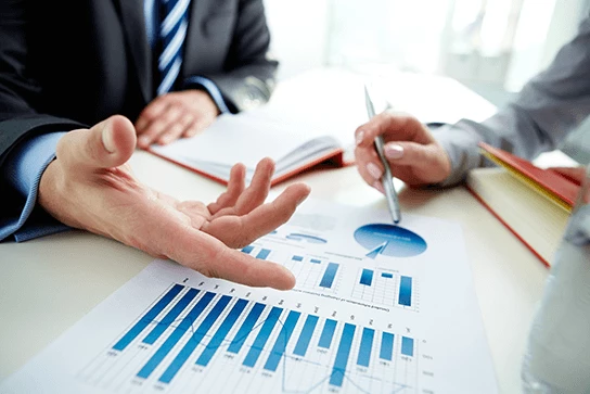 A person points to a chart while another person looks on.