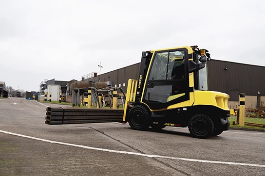 Hyster forklift lifts beams of lumber in an outdoor setting